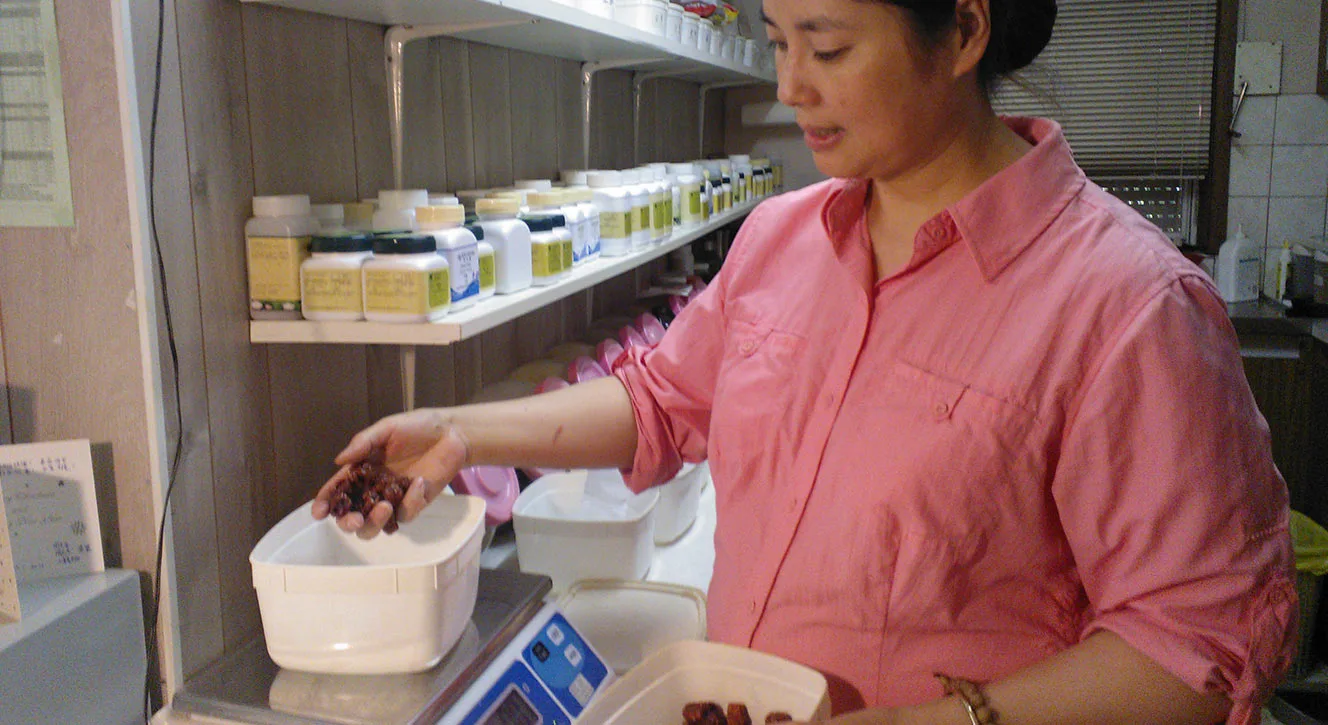 Practitioner weighing dried herbs at the dispensary