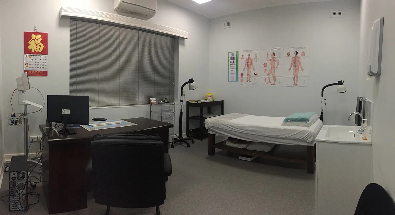 An Evergreen acupuncture treatment room — desk, treatment bed, anatomy charts, calm and orderly